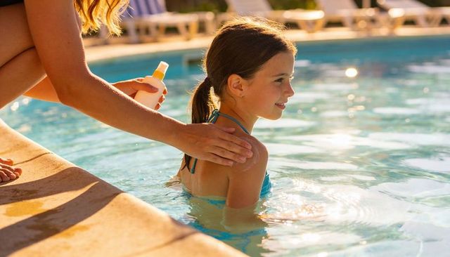 Parent applying sunscreen on child poolside for sun safety and summer fun