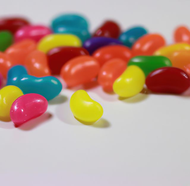 Close up of multiple colourful sweet jelly beans on white background. Sweets, beans and food concept.