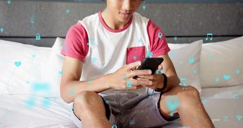 Teen using smartphone on bed with digital network icons showing connectivity and apps