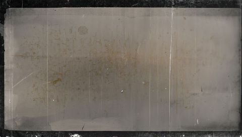 Worn glass plate showing foxing, vertical creases, central speck and dark border patina