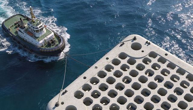 Tugboat towing perforated concrete block offshore showing towlines cleats and wake