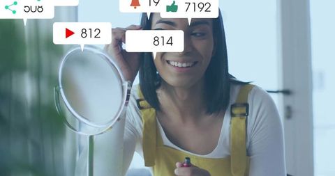 Man wearing yellow overalls applying mascara with social media icon notifications