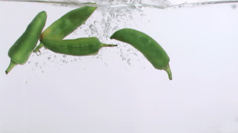 Green Peppers Falling into Water in Slow Motion