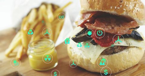 Melting bacon cheeseburger with fries and mustard, green sustainability icon overlay for food tech
