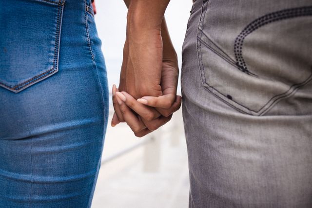 This image captures a close-up view of a couple holding hands while wearing casual jeans. It symbolizes love, connection, and togetherness, making it ideal for use in relationship blogs, lifestyle articles, and romantic-themed advertisements.