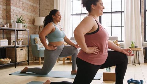 Plus-Size Women Stretching Together in Bright Loft Home Workout Session
