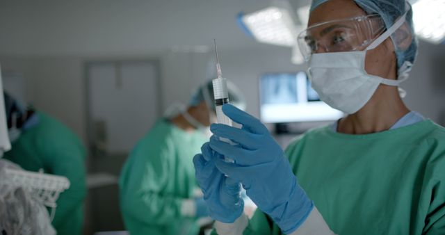 Surgeon Wearing Protective Gear Preparing Syringe in Operating Room - Download Free Stock Images Pikwizard.com