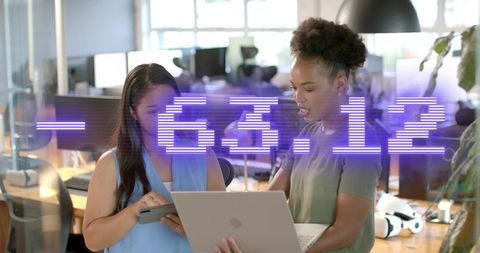 Businesswomen Analyzing Financial Data on Laptop in Modern Office