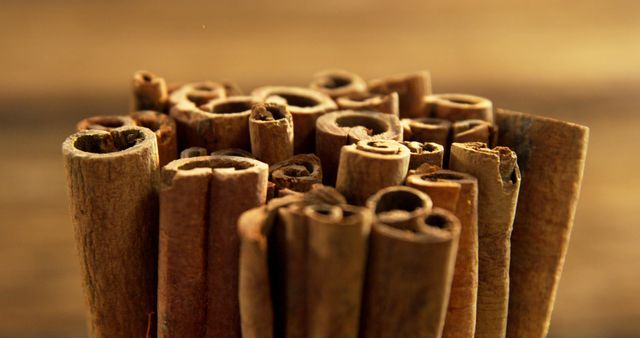 A bundle of cinnamon sticks is tightly packed together, showcasing their textured bark and warm brown tones. Cinnamon is a popular spice used in various cuisines for its distinctive flavor and aroma.