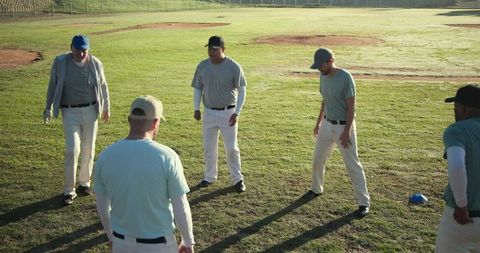 Adult baseball team warming up in semicircle on grassy infield at sunrise practice