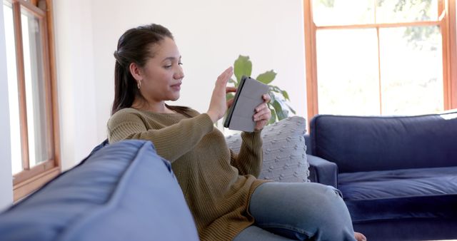 Young woman using digital tablet on blue sofa at home - Download Free Stock Images Pikwizard.com