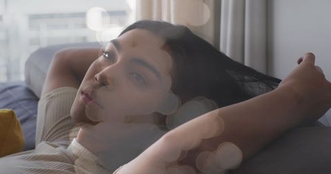 Dreamy Portrait of Relaxed Woman on Sofa Amidst Light Flare