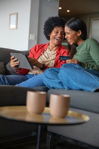 Joyful Friends Browsing on Tablet at Home with Credit Card
