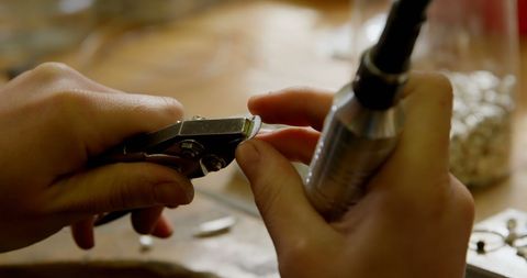 Skilled Jeweler Crafting Unique Jewelry Piece with Precision Tools