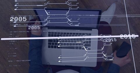 Overhead view of woman working on laptop, holding smartphone and data overlays