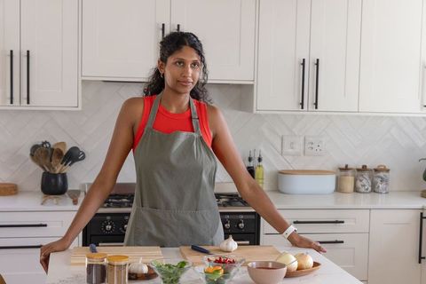 Indian home cook preparing fresh ingredients on modern kitchen island leaning on counter