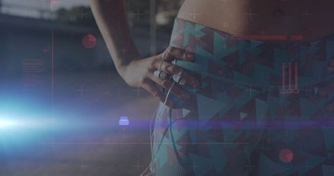 Adjusting patterned leggings holding wired earbuds at dusk with futuristic hud overlay