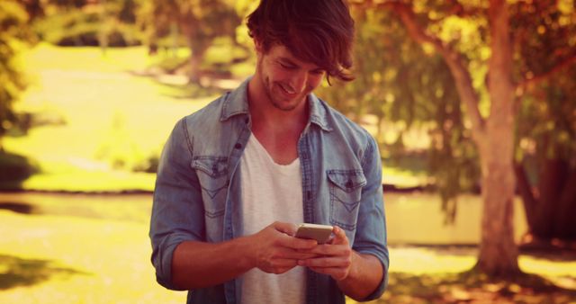 Young Man Using Smartphone in Sunny Park - Download Free Stock Images Pikwizard.com