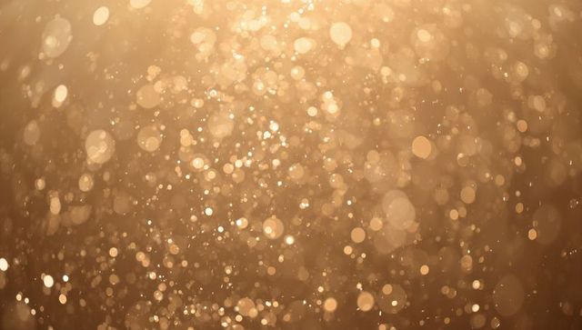 Golden bokeh particles floating in warm backlight, shimmering glitter and dust halo