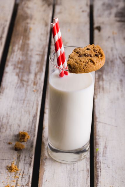 Close-up of milk glass with cookie and straws on wooden table, copy space. unaltered, food, drink and healthy eating.