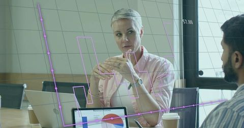 Business professionals analyzing data with digital chart overlay in modern meeting