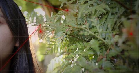Framing asian woman revealing profile in sunlit garden with ferns, bokeh, cinematic grid
