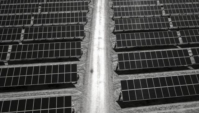 Aerial view of ground-mounted solar farm with geometric rows of photovoltaic panels