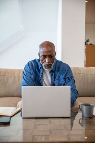 Senior Man Focused Working on Laptop in Modern Living Room