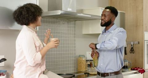 African american couple chatting in modern kitchen, man opening bottle, woman holding mug
