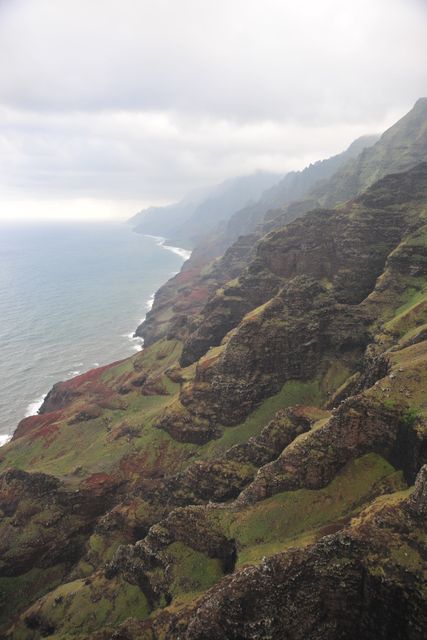 Cliffs meet the ocean creating stunning scenic view on Hawaiian coastline. Ideal for travel guides, nature-themed collections, postcards, calendars highlighting beautiful natural landscapes.