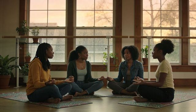 Black women practicing circle meditation and mindful conversation in sunlit studio