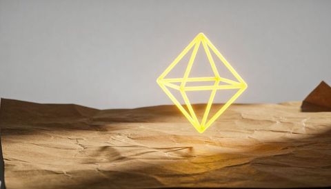 Floating neon octahedron glowing over crumpled kraft paper minimal geometric light