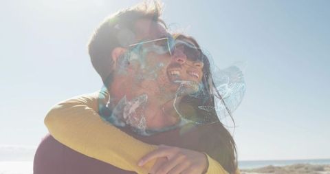 Couple embracing on sunlit beach with jellyfish double exposure and lens flare