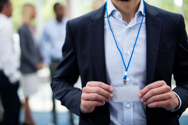 Businessman holding ID card at a conference, highlighting professional networking and corporate events. Ideal for use in business-related content, articles on professional events, corporate identity, and networking opportunities.