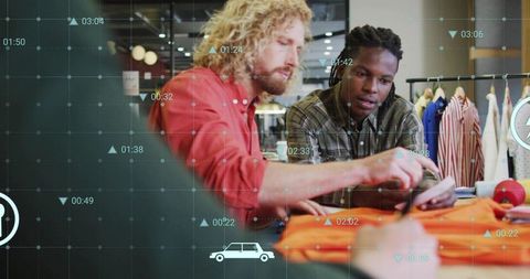 Designers collaborating over orange garment using smartphone with data overlay