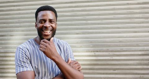 Cheerful Young Man Smiling Against Urban Metal Shutter Background