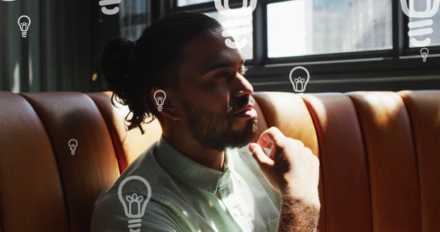 Pensive Young Man with Creative Light Bulb Icons in Café - Download Free Stock Images Pikwizard.com