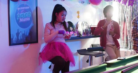 Asian woman wearing pink tulle skirt at neon disco party bar with pool table vibes