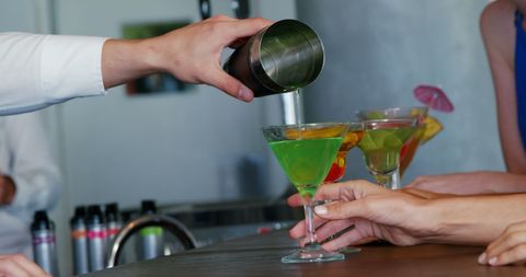Bartender pouring vibrant cocktails with precision at a trendy bar