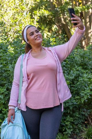African american woman taking selfie after outdoor workout in pink jacket and leggings