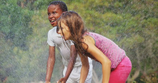 Children enjoying a hot summer day playing in the sprinkler, laughing and smiling outside in a lush garden. Perfect for use in advertisements, websites, and brochures related to summer camp, children's activities, outdoor fun, and family bonding.