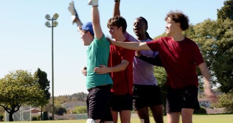 Youth cricket team celebrating wicket: indian keeper leaping while teammates cheer outdoors