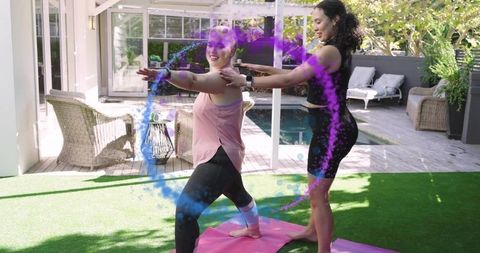 Outdoor yoga instructor guiding student in warrior pose on backyard mats, smartwatch, pool