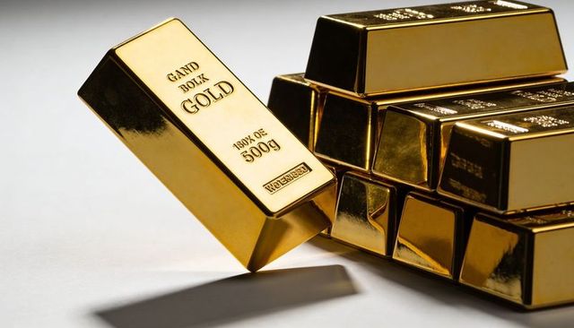 Stacked gold bars and single 500g bullion bar leaning, reflective ingots for finance