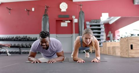 Diverse Couple Planking Together in Gym Focused on Fitness