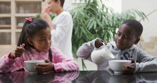 Siblings Enjoying Breakfast with Milk and Cereal at Kitchen Counter - Download Free Stock Images Pikwizard.com