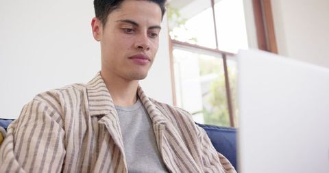 Concentrated Man in Striped Jacket Working on Laptop in Home