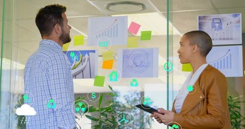Business team brainstorming growth strategy on glass wall with charts and eco icons