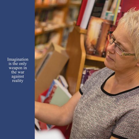 Mature woman reading books in library, pondering imaginative quote