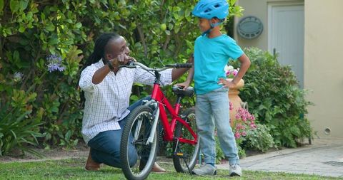 Father Teaching Young Son to Ride Bicycle in Garden